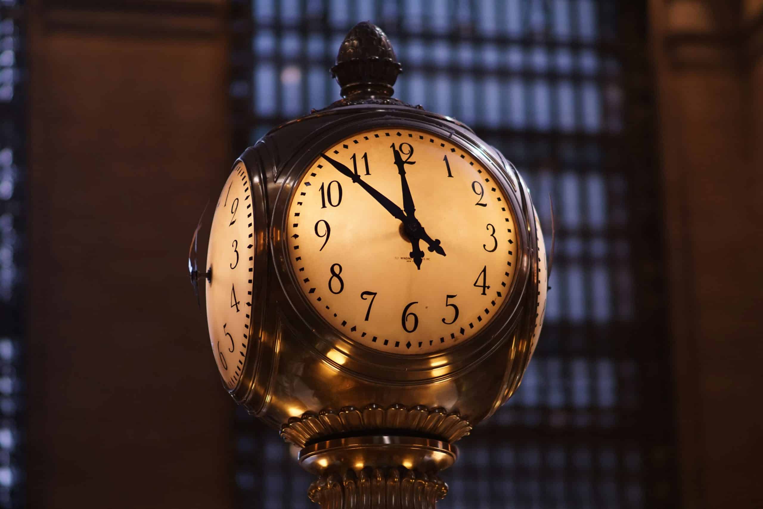 Elegant klokke med messingdetaljer i en travel togstasjon, som illustrerer viktigheten av tid og timeprisberegning.